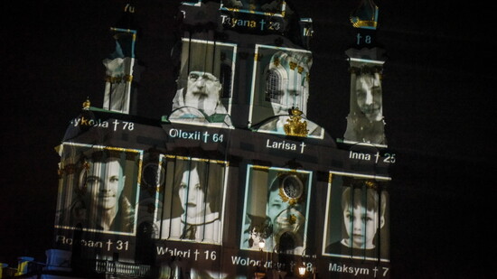 Porträtfotos von Verstorbenen erscheinen als Projektion auf der Fassade der St. Andreas Kirche in Kiew.
