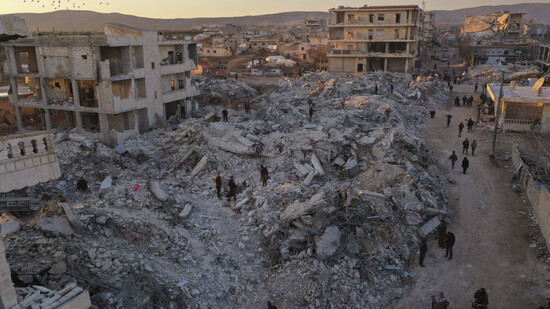 Menschen gehen an eingestürzten Gebäuden im syrischen Jinderis vorbei. Foto: Ghaith Alsayed/AP/dpa