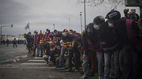 Gewerkschaftsmitglieder schützen sich bei Zusammenstößen mit Polizeibeamten während einer Demonstration in Lyon. Foto: Laurent Cipriani/AP/dpa