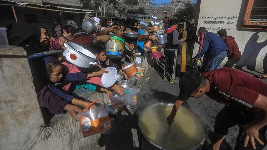 ARCHIV - Palästinenser versammeln sich mit Töpfen, um an einer von einer Wohltätigkeitsorganisation eingerichteten Spendenstelle Lebensmittel entgegenzunehmen. Foto: Mohammed Talatene/dpa