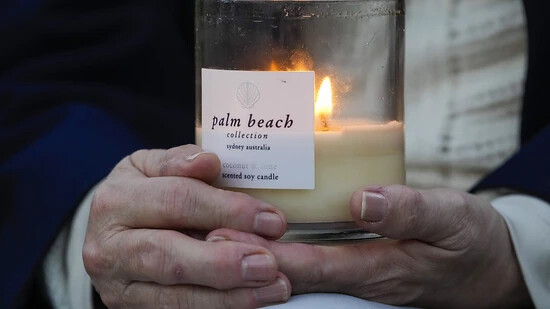 Eine Person hält eine Kerze während einer Mahnwache in Erinnerung an die Opfer der Bluttat in der Bondi Junction Mall in Sydney vor knapp einer Woche. Foto: Mark Baker/AP/dpa