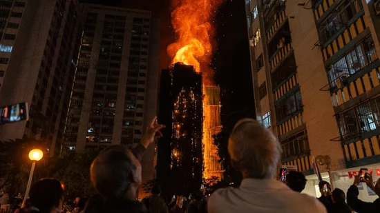 dpatopbilder - Menschen betrachten die Flammen, die ein Gebäude verschlingen, nachdem im Wang Fuk Court, einer Wohnsiedlung im Stadtteil Tai Po in den New Territories von Hongkong, ein Feuer ausgebrochen ist. Foto: Chan Long Hei/AP/dpa