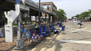 Leere Stühle stehen auf dem Bürgersteig, nachdem die Teilnehmer der Parade in Highland Park (Illinois) nach Schüssen geflohen sind. Foto: Lynn Sweet/Chicago Sun-Times/AP/dpa