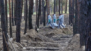 Ukrainische Hilfskräfte bergen eine Leiche aus einem Massengrab bei Isjum in der Ostukraine. (Archivbild)