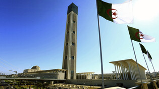 ARCHIV - Algerische Flaggen wehen neben der Großen Moschee in Algier. 49 Menschen wurden von einem Gericht in Algerien zum Tode verurteilt. Foto: Toufik Doudou/AP/dpa