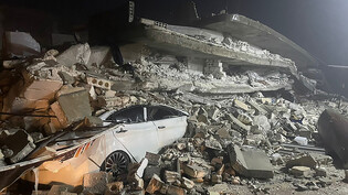 Ein Auto ist unter den Trümmern eines eingestürzten Gebäudes in der Stadt Azmarin in der nordsyrischen Provinz Idlib zu sehen. Zwei heftige Erdbeben haben kurz nacheinander am frühen Montagmorgen den Südosten der Türkei erschüttert. Foto: Ghaith Alsayed…