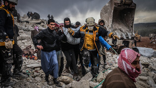 Zivilisten und Mitglieder des syrischen Zivilschutzes führen Such- und Rettungsmaßnahmesuchen in den Trümmern eines zerstörten Gebäudes durch. Foto: Anas Alkharboutli/dpa