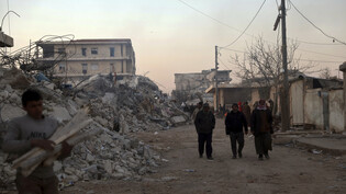 Menschen gehen an eingestürzten Gebäuden vorbei. Foto: Ghaith Alsayed/AP/dpa