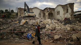Ein Mann geht an einem eingestürzten Gebäude in Adiyaman vorbei. Foto: Emrah Gurel/AP/dpa