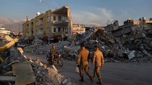Menschen gehen an den Trümmern zerstörter Gebäude vorbei. Zweieinhalb Wochen nach der Erdbeben-Katastrophe gibt es noch immer Nachbeben. Foto: David Zorrakino/EUROPA PRESS/dpa