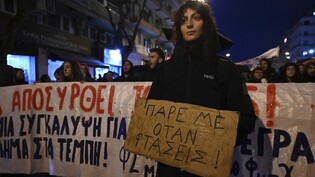 Eine Frau hält ein Plakat mit der Aufschrift «Ruf mich an, wenn du ankommst» während einer Demonstration. Trauer und Entsetzen herrschen in Griechenland nach dem schweren Zugunglück mit mehreren Toten und Verletzten. Foto: Giannis Papanikos/AP