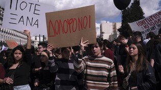 Menschen halten bei einer Demonstration vor dem Parlament in Athen Plakate hoch, auf denen in griechisch die Worte «Mörder» (M-l) und «Nie wieder!» stehen. Foto: Aggelos Barai/AP