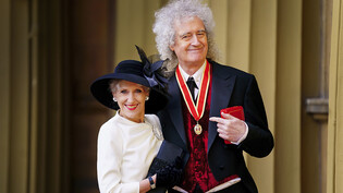 Sir Brian May (r), Musiker und Tierschützer aus Großbritannien, steht nach Vergabe des Ordens mit seiner Frau Anita Dobson am Buckingham Palast, nachdem er von König Charles III. zum Ritter geschlagen wurde. Foto: Victoria Jones/PA Pool/AP