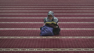 Eine Muslima liest in Jakarta in einer Moschee den Koran. Foto: Tatan Syuflana/AP/dpa