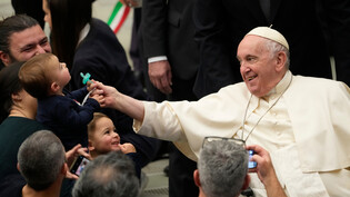 Aufruf zur Genügsamkeit: Papst Franziskus nimmt einem Kind im Vatikan am Ende seiner wöchentlichen Generalaudienz am Mittwoch, 14. Dezember 2022, scherzhaft den Schnuller weg. Papst Franziskus rief am Mittwoch zu einem «bescheidenen» Weihnachtsfest in diesem Jahr auf.