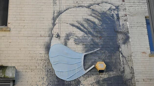 ARCHIV - Das Wandgemälde "Das Mädchen mit dem Perlenohrring", das von dem britischen Streetart-Künstler Banksy stammen soll, auf dem Hanover Place, hat als Reaktion auf die Coronavirus-Pandemie eine Gesichtsmaske bekommen. Foto: Ben Birchall/PA Wire/dpa …