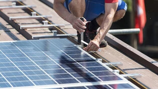 Chance: Ein Arbeiter installiert Solarmodule auf einem Dach. 