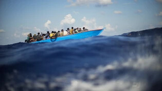 ARCHIV - Migranten sitzen in einem Holzboot südlich der italienischen Insel Lampedusa auf dem Mittelmeer. Foto: Francisco Seco/AP/dpa