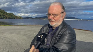 ARCHIV - Der norwegische Schriftsteller Jon Fosse spricht mit einer Journalistin auf einer Werft, nachdem er den diesjährigen Literaturnobelpreis gewonnen hat. Die Pressekonferenz zur Übergabe der Auszeichnung am 10. Dezember 2023 sagte er nun ab. Foto:…