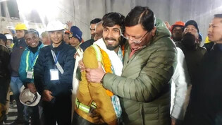 HANDOUT - Pushkar Singh Dhami (r), Ministerpräsident von Uttarakhand, begrüßt einen Arbeiter, der aus dem eingestürzten, sich im Bau befindenden, Tunnel gerettet wurde. Beim Tunnel-Drama in Indien sind alle 41 eingeschlossenen Arbeiter aus dem Berg…