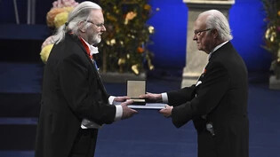 Jon Fosse (l) erhält den Literaturnobelpreis 2023 von König Carl XVI. Gustaf von Schweden während der Nobelpreisverleihung in der Konzerthalle in Stockholm. Foto: Claudio Bresciani/TT News Agency/AP/dpa