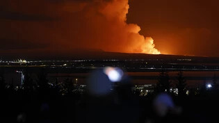 Menschen beobachten, wie der Nachthimmel nach dem Ausbruch eines Vulkans im Südwesten Islands erhellt wird. Foto: Brynjar Gunnarsson/AP