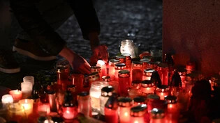 Eine Person entzündet eine Kerze vor dem Gebäude der Philosophischen Fakultät der Karls-Universität in Prag. Foto: Denes Erdos/AP/dpa