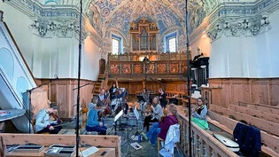 Pause während der CD-Aufnahmen in Zernez: Das Orchesters Le phénix bereitet sich im Kirchenschiff auf den nächsten Take vor, hinter ihnen auf der Empore geht Organist Hannfried Lucke die entsprechende Passage noch einmal durch.