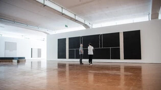 Zurück in Trun – zurück zuhause! Das Triptychon von Matias Spescha wird vom Architekten Remo Derungs (links) und von Kurator Peter Fischer in der neuen Ausstellungshalle Spazi Spescha begutachtet.
