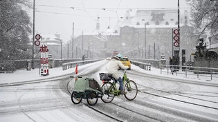 Trotz Schnee und Wind: Eine Frau fährt mit dem Velo über den Helvetiaplatz in Bern.