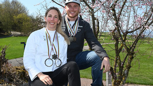 Das Ergebnis eines erfolgreichen Winters: Ladina Jenny und Dario Caviezel zeigen ihre Medaillen aus der Saison 2022/23.