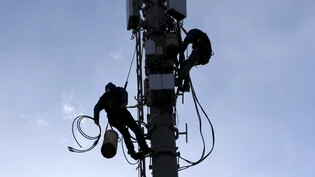 Die Swisscom rüstet auf: Techniker verkabeln 5G-Mobilfunkantennen auf einem Mast in Genf, der bereits mit 4-G-Antennen ausgerüstet ist. 