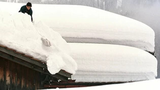 Wenn vor lauter Schnee das Haus nicht mehr zu sehen ist: In aufwendiger Schaufelarbeit versucht ein Hausbesitzer in Klosters, sein Dach von den tonnenschweren Schneemassen zu befreien. 